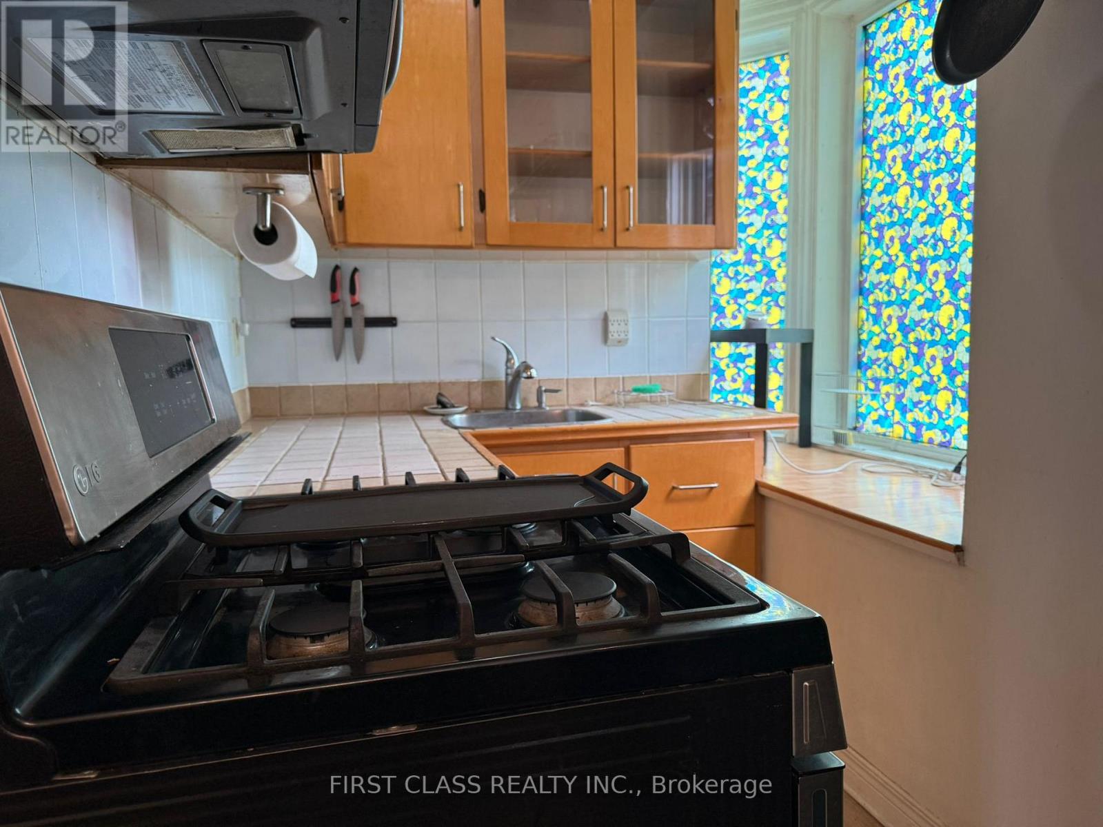 A kitchen with a black stove top oven and wooden cabinets.