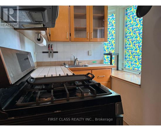 A kitchen with a black stove top oven and wooden cabinets.