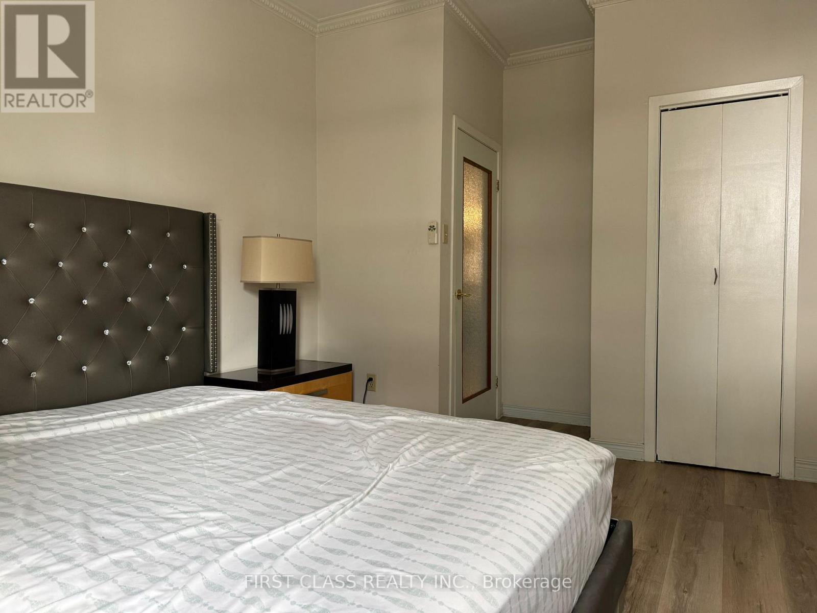 A bedroom with a large bed and a lamp on a side table.