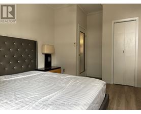 A bedroom with a large bed and a lamp on a side table.
