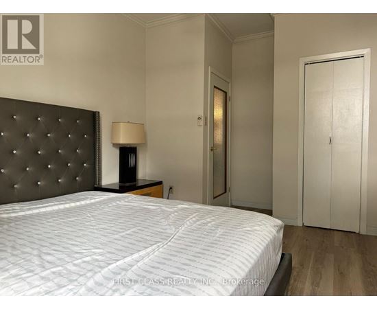 A bedroom with a large bed and a lamp on a side table.