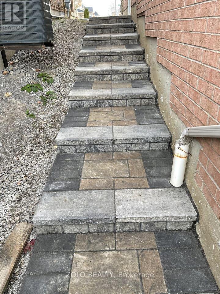 A set of stairs with a brick wall on one side and a metal pipe on the other.