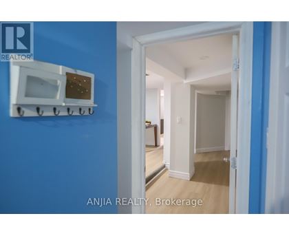 A white microwave oven is mounted on a blue wall.