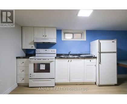 A kitchen with white appliances and cabinets against a blue wall.