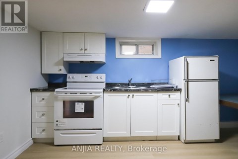 A kitchen with white appliances and cabinets against a blue wall.