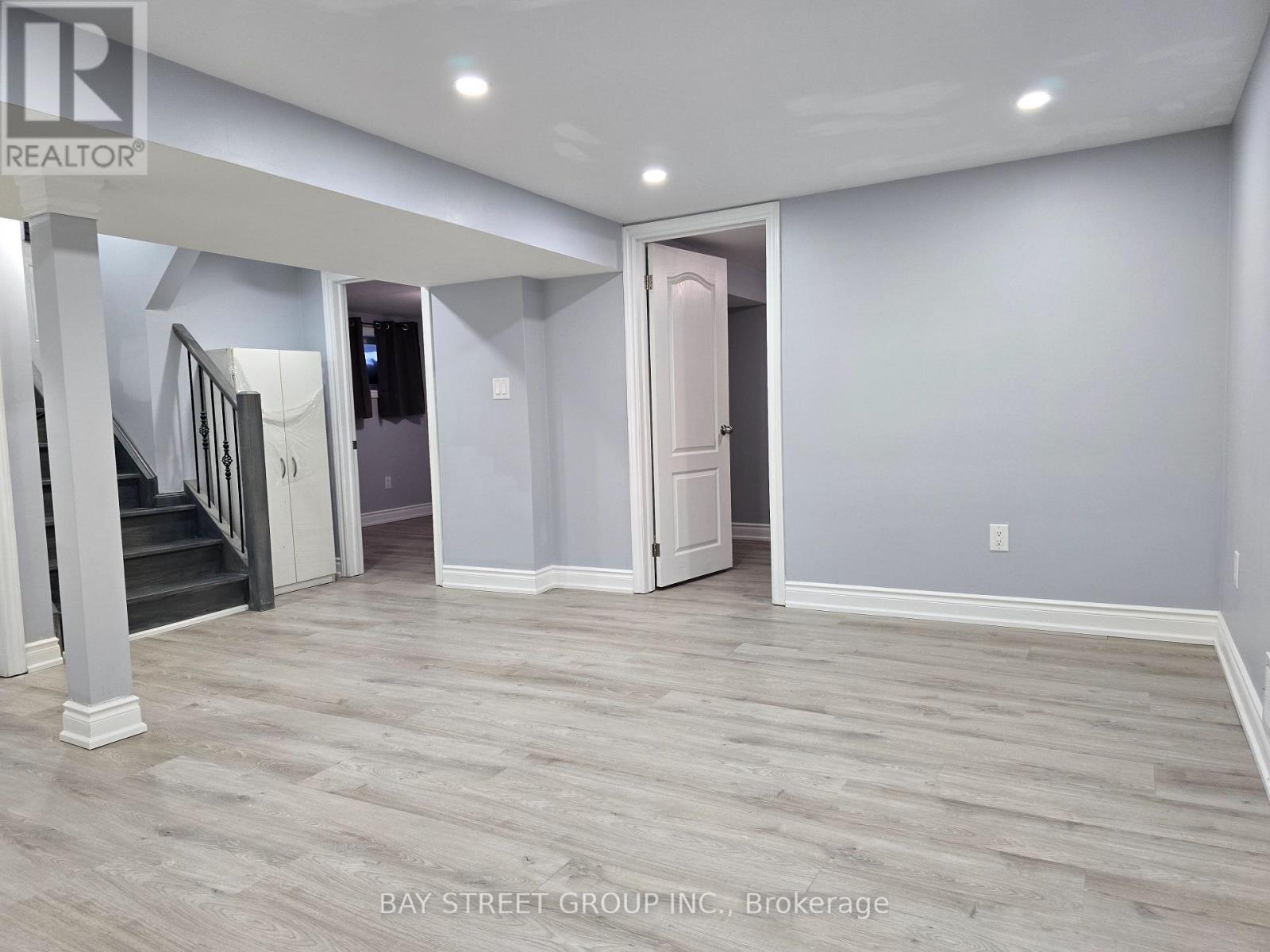 A spacious room with light grey walls and a wooden floor.