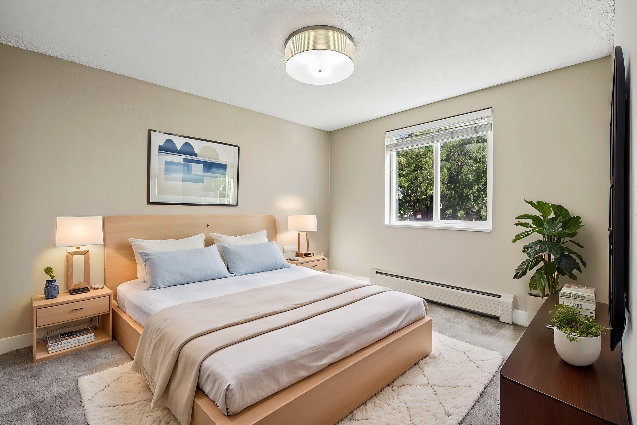 A bedroom with a large bed and a painting on the wall.