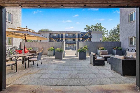 A patio with a table and chairs is surrounded by a brick wall.
