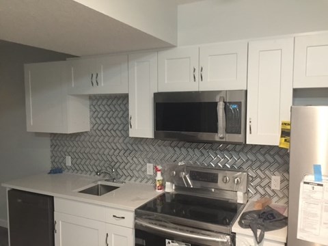 A kitchen with white cabinets and a black dishwasher.