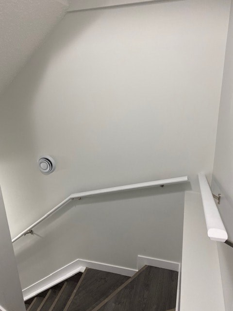 A stairway with a white hand rail and a light on the wall.
