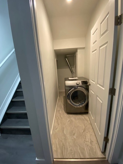 A washing machine is in a small space between a staircase and a door.