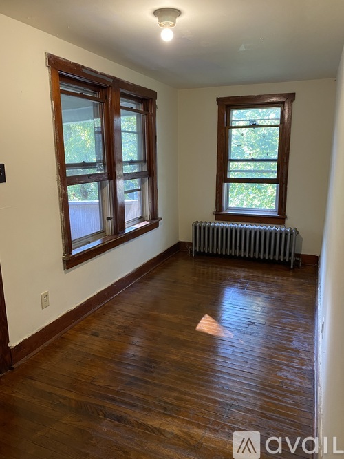 A room with wooden floors and a window with a view of trees.
