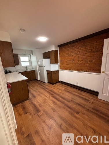 A kitchen with wooden floors and a brick wall.