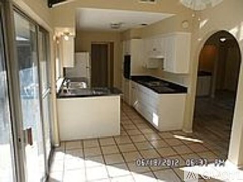 A kitchen with white cabinets and a black counter top.