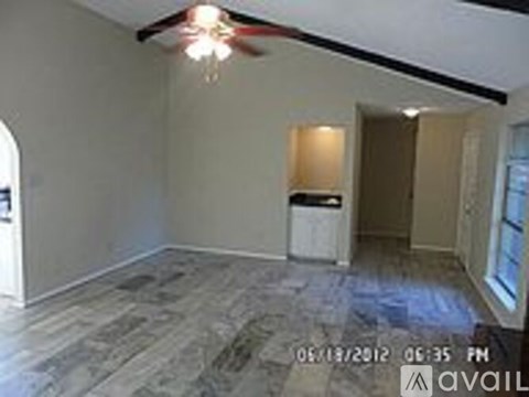 A room with a fan on the ceiling and a trash bin on the floor.