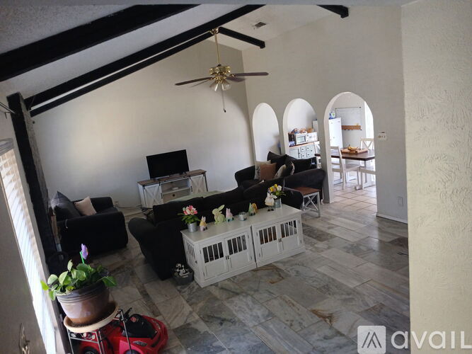 A living room with a fan, couches, and a table with a vase of flowers on it.