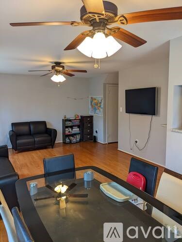 A living room with a black leather couch and a ceiling fan.