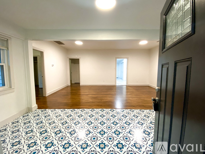A room with a patterned tile floor and wooden flooring in the background.