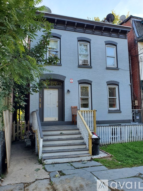 A grey house with a white picket fence and a black door.