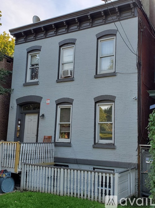 A grey two-story house with a white picket fence.