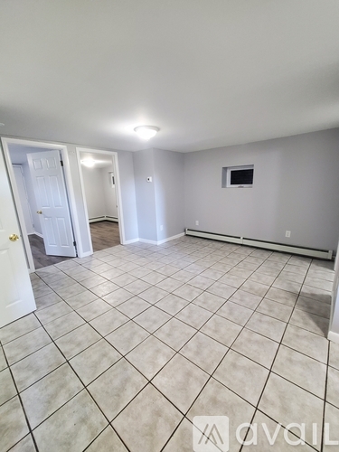 A spacious room with tiled flooring and a wall-mounted television.
