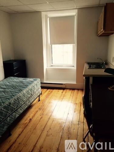 A room with a bed, a desk, and a window.