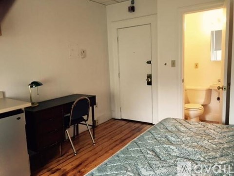A bedroom with a bed, desk, and chair.