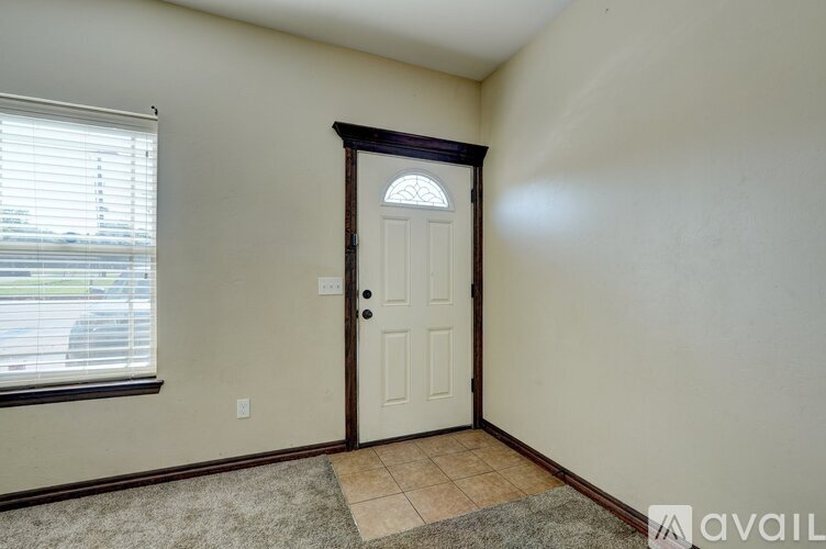 A room with a door, window, and a rug on the floor.