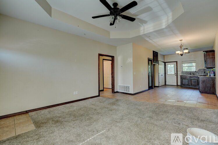 A spacious living room with a ceiling fan and a carpeted floor.