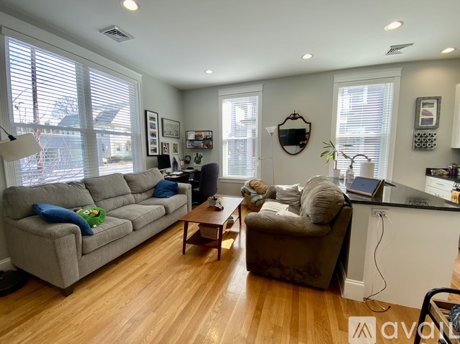 A living room with a grey couch, a brown armchair, and a wooden floor.