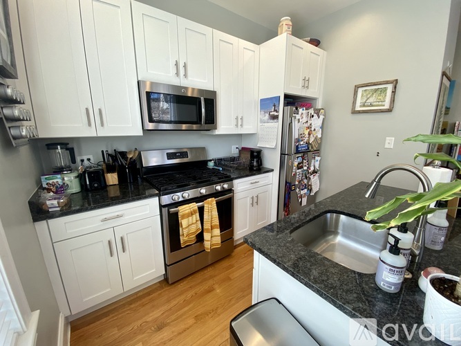 A kitchen with white cabinets and black countertops.