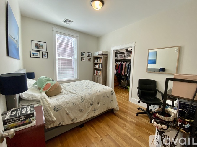 A bedroom with a bed, desk, chair, and bookshelf.