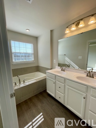 A bathroom with a tub, sink, and mirror.
