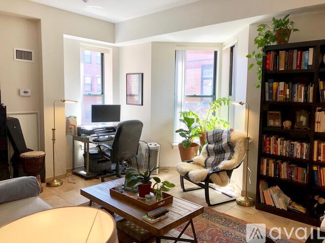 A living room with a chair, a table, a bookshelf, and a window.