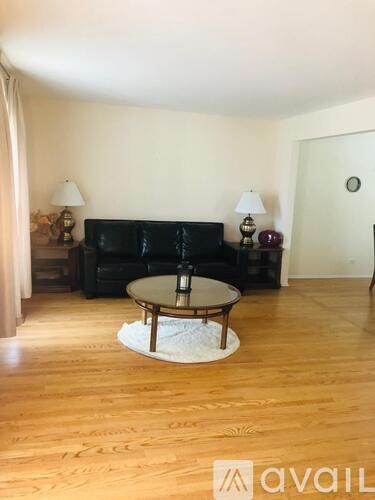 A living room with a black couch, a coffee table, and two lamps.