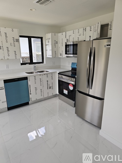 A kitchen with a refrigerator, sink, and oven is under construction.