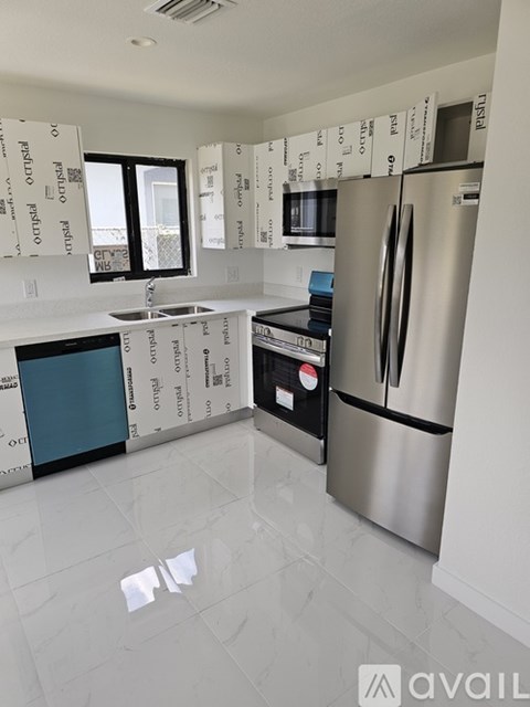 A kitchen with a refrigerator, sink, and oven is under construction.