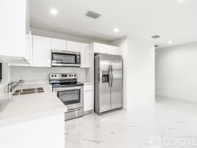 A modern kitchen with white appliances and marble countertops.