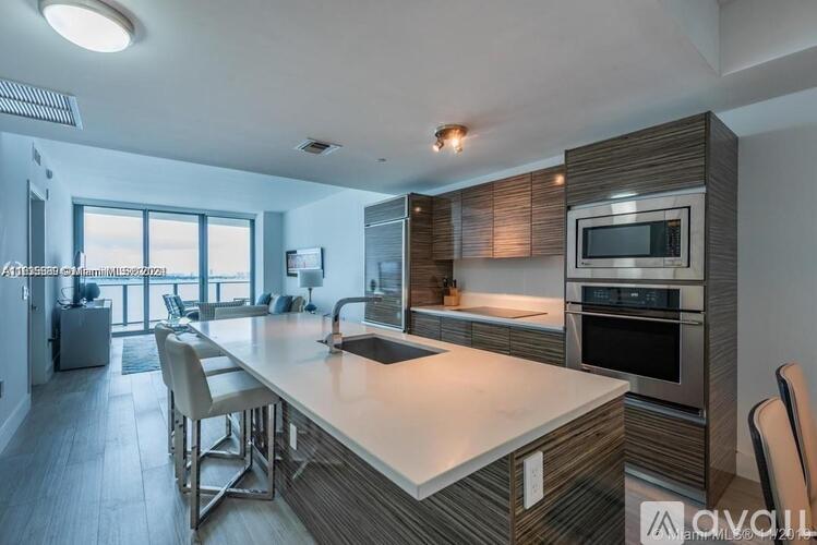 A modern kitchen with a large island and stainless steel appliances.