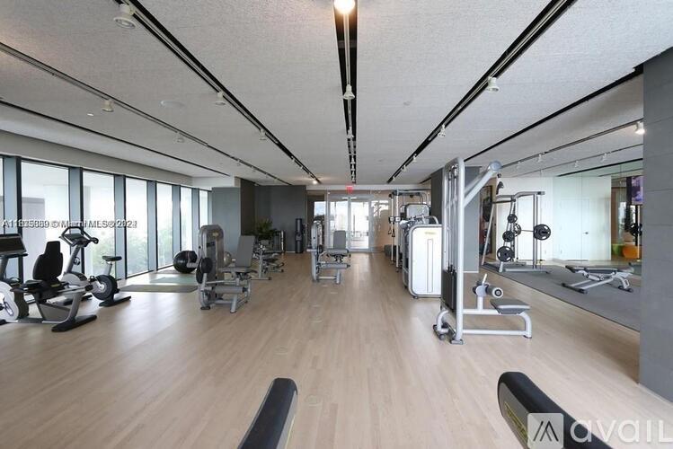 A spacious gym with a variety of equipment and a long mirrored wall.