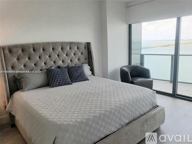 A bedroom with a large bed and a chair.