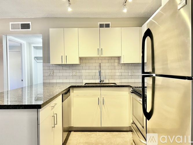 A kitchen with white cabinets and black countertops.