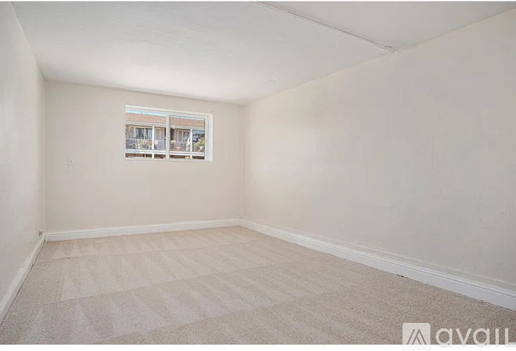 A room with a carpeted floor and a window showing a building outside.