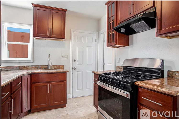A kitchen with brown cabinets and a black stove top oven.