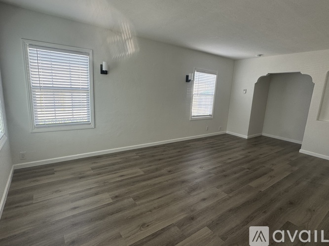 A room with wooden flooring and a window with blinds.
