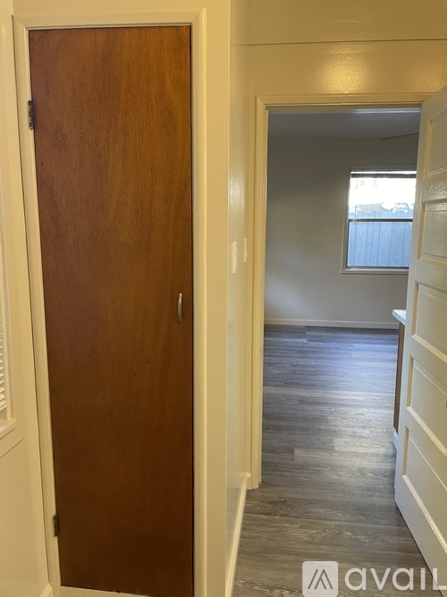 A brown door is on the left and a hallway is on the right.