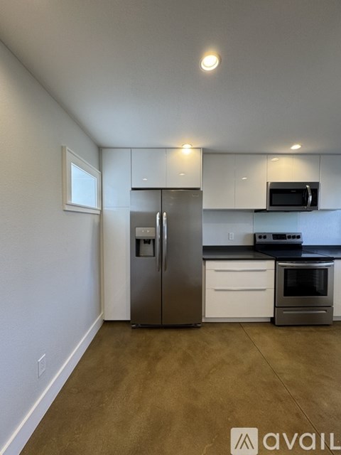 A kitchen with white cabinets and a stainless steel refrigerator.
