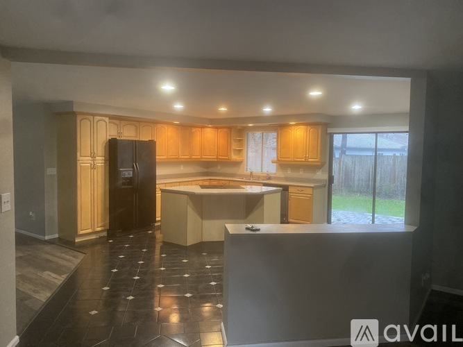 A kitchen with wooden cabinets and a black refrigerator.