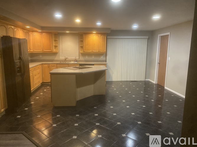 A kitchen with wooden cabinets and a black fridge.
