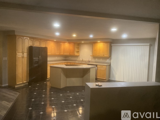 A kitchen with wooden cabinets and a black fridge.